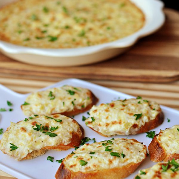 This delicious Artichoke Bruschetta is a great easy appetizer! Cheesy artichoke dip is spread on baguette slices and broiled until golden and bubbly for an appetizer that’s fancy yet no-fuss.
