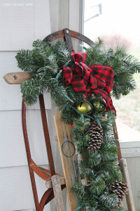 Add some holiday accessories such as pinecones, bells, lights, and greenery to a vintage snow sled to decorate for winter!