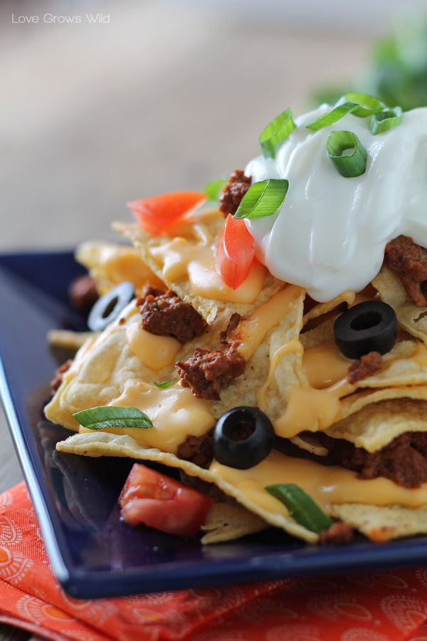 Chili Cheese Nachos are the perfect party food, with layers of beefy chili, homemade cheese sauce, and piled high with tasty toppings!