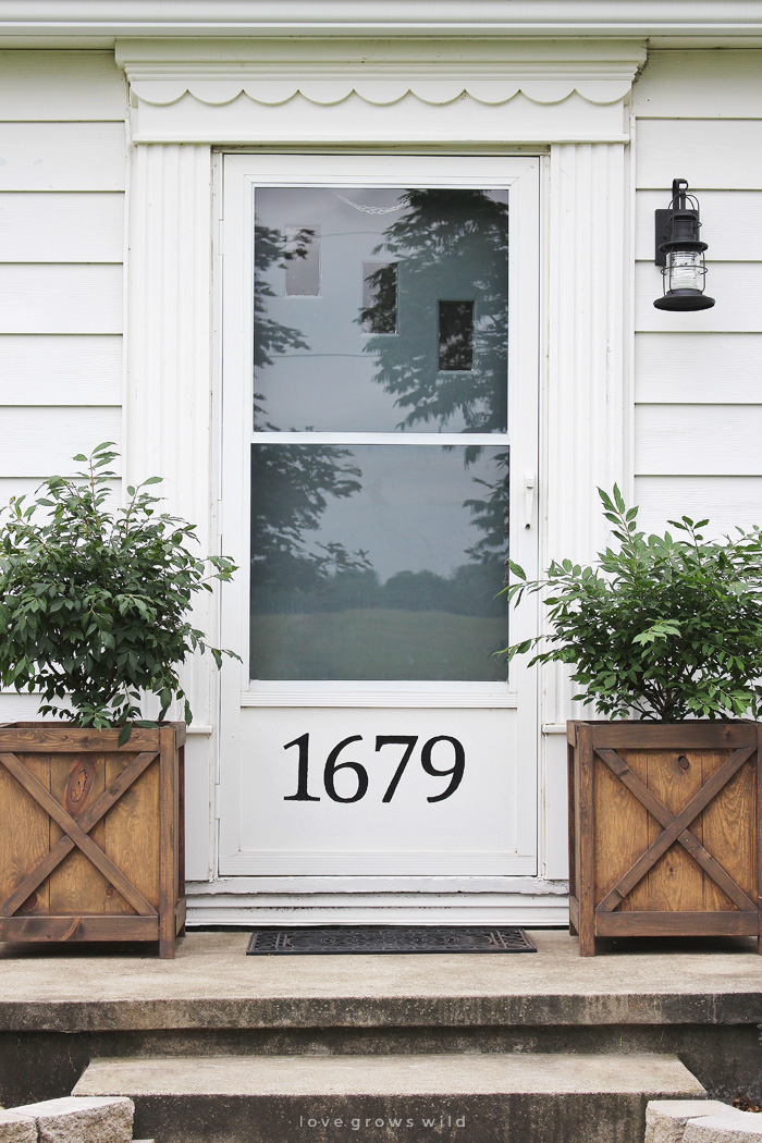 Get all the details of this charming front porch makeover featuring DIY wood planters and a lantern light fixture. | LoveGrowsWild.com