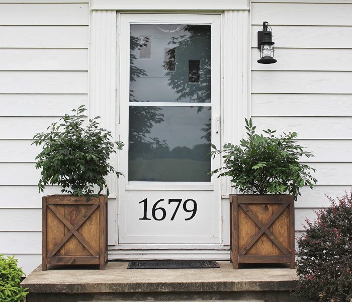 Get all the details of this charming front porch makeover featuring DIY wood planters and a lantern light fixture. | LoveGrowsWild.com