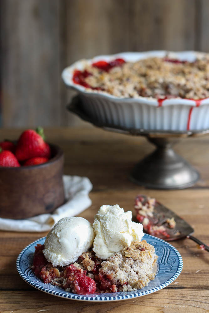 Delicious strawberry crisp made with fresh berries and a crunchy topping of oats and pecans. Serve warm out of the oven with a scoop of vanilla ice cream! | LoveGrowsWild.com