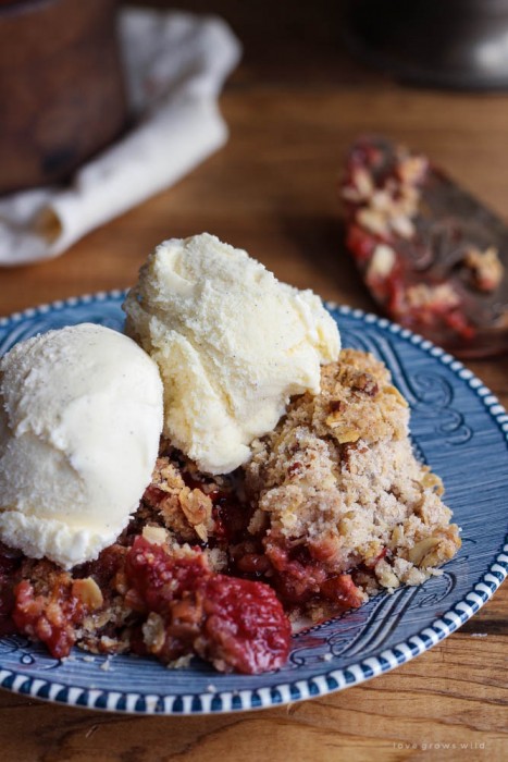 Delicious strawberry crisp made with fresh berries and a crunchy topping of oats and pecans. Serve warm out of the oven with a scoop of vanilla ice cream! | LoveGrowsWild.com