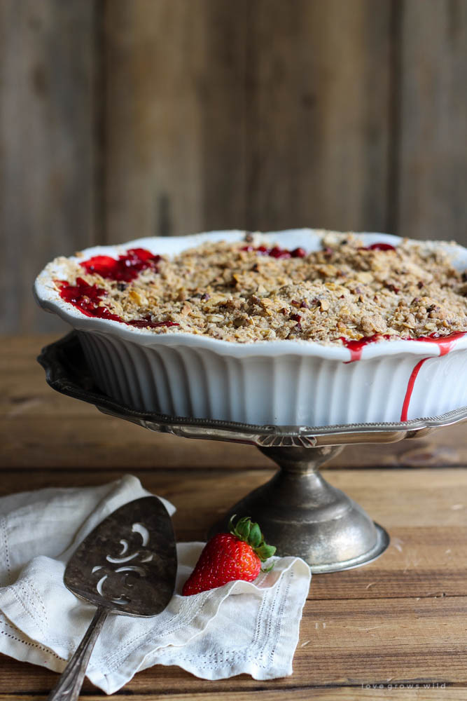 Delicious strawberry crisp made with fresh berries and a crunchy topping of oats and pecans. Serve warm out of the oven with a scoop of vanilla ice cream! | LoveGrowsWild.com