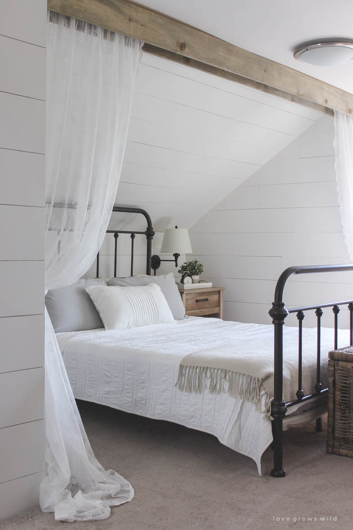 This cozy sleeping nook was created by adding a faux wood beam and lace curtains over the bed, and the results are amazing! See how to do this project in your home at LoveGrowsWild.com