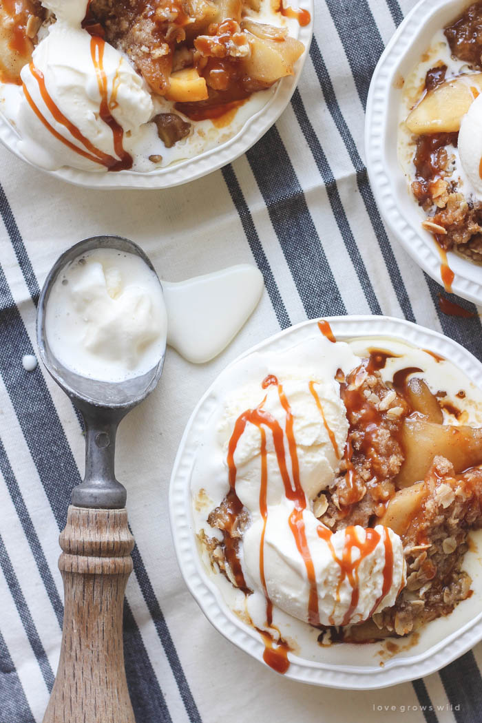 Warm salted caramel apple crisp topped with scoops of vanilla ice cream and more salted caramel drizzled over top... the perfect dessert! Get the recipe at LoveGrowsWild.com