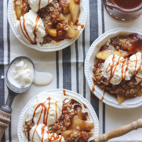 Warm salted caramel apple crisp topped with scoops of vanilla ice cream and more salted caramel drizzled over top... the perfect dessert! Get the recipe at LoveGrowsWild.com