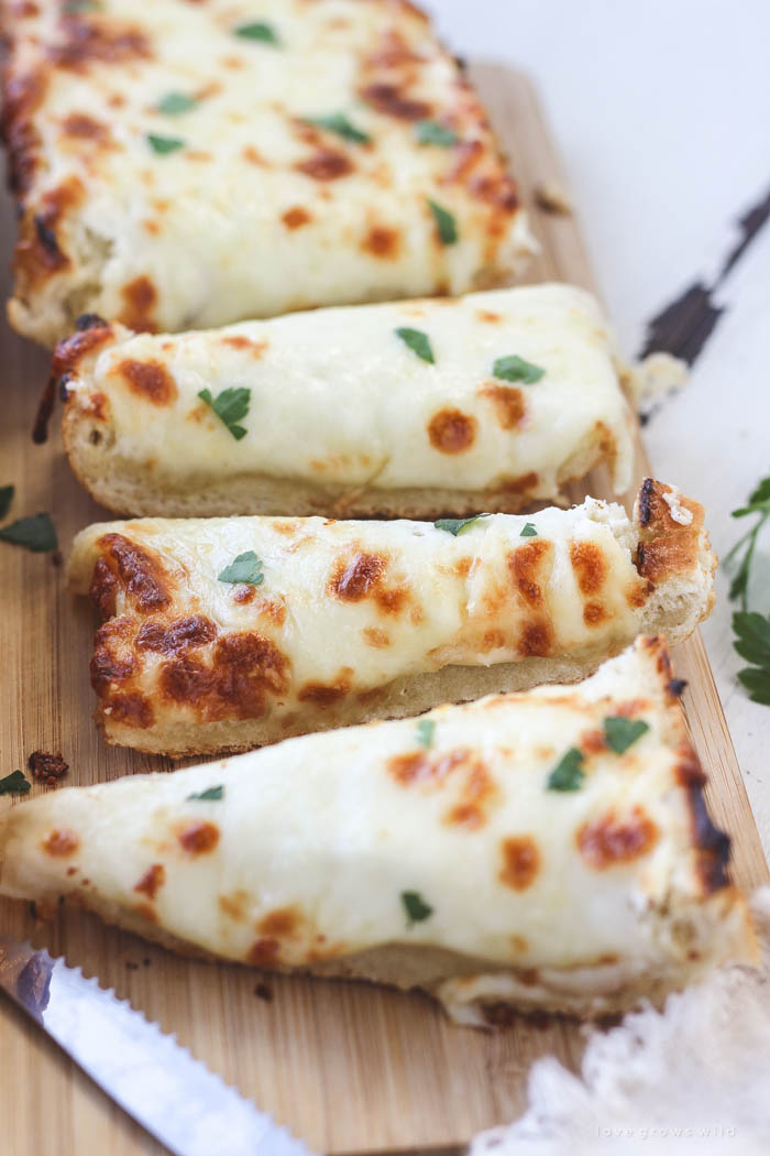 Delicious, extra cheesy garlic bread that is perfectly crusty on the outside and soft and tender on the inside! Find out the secret ingredient at LoveGrowsWild.com