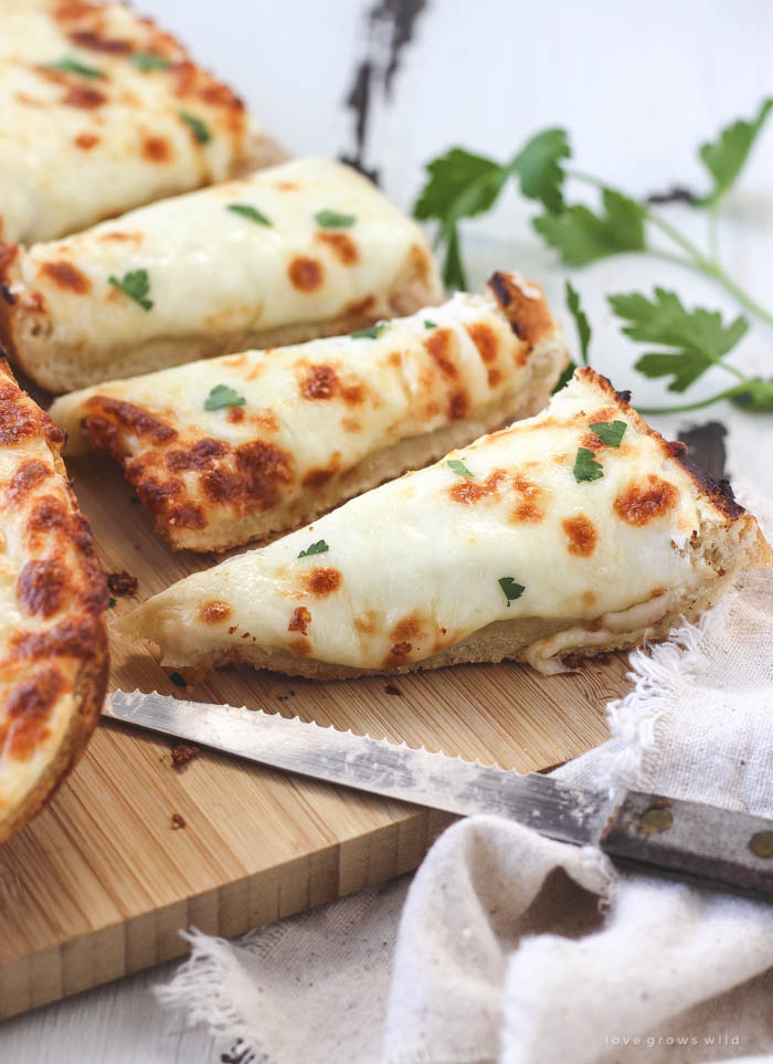 Delicious, extra cheesy garlic bread that is perfectly crusty on the outside and soft and tender on the inside! Find out the secret ingredient at LoveGrowsWild.com