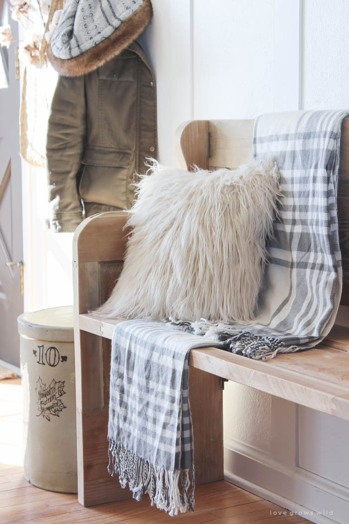 This simple farmhouse entryway is perfectly decorated for winter with large coat hooks, a rustic bench, and a place for snow-covered boots. See more photos at LoveGrowsWild.com