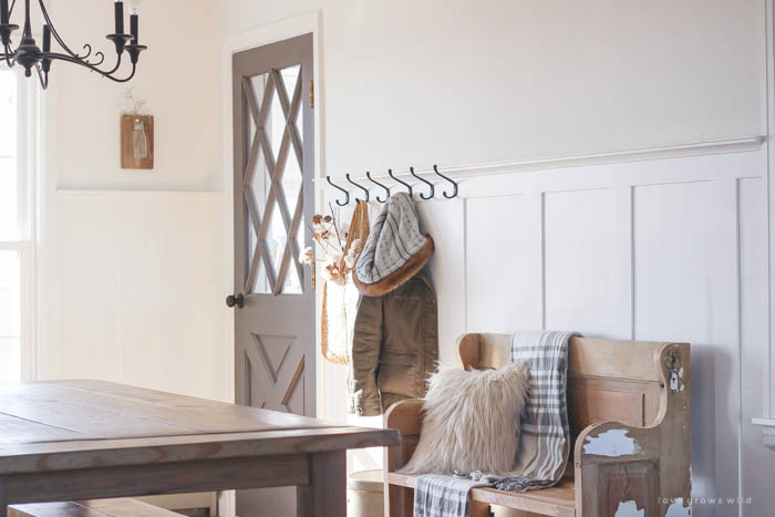 This simple farmhouse entryway is perfectly decorated for winter with large coat hooks, a rustic bench, and a place for snow-covered boots. See more photos at LoveGrowsWild.com