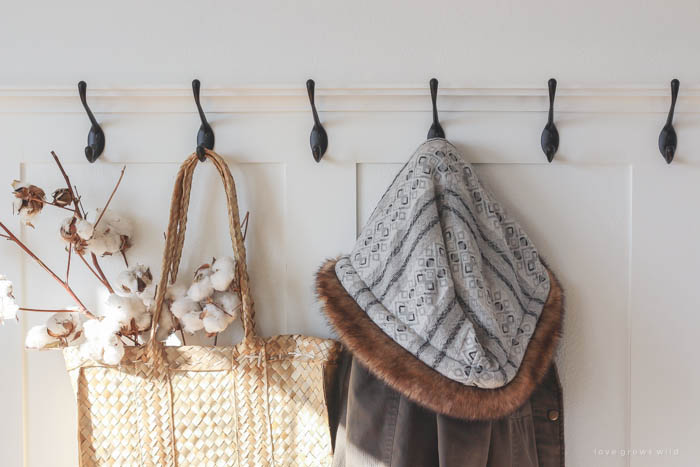 This simple farmhouse entryway is perfectly decorated for winter with large coat hooks, a rustic bench, and a place for snow-covered boots. See more photos at LoveGrowsWild.com