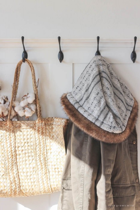 This simple farmhouse entryway is perfectly decorated for winter with large coat hooks, a rustic bench, and a place for snow-covered boots. See more photos at LoveGrowsWild.com