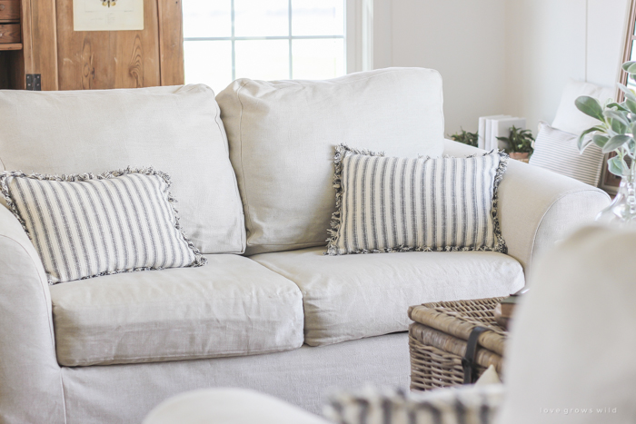 A cozy farmhouse living room with beautiful linen slipcovered sofas. See how to get this custom slipcovered look at LoveGrowsWild.com!