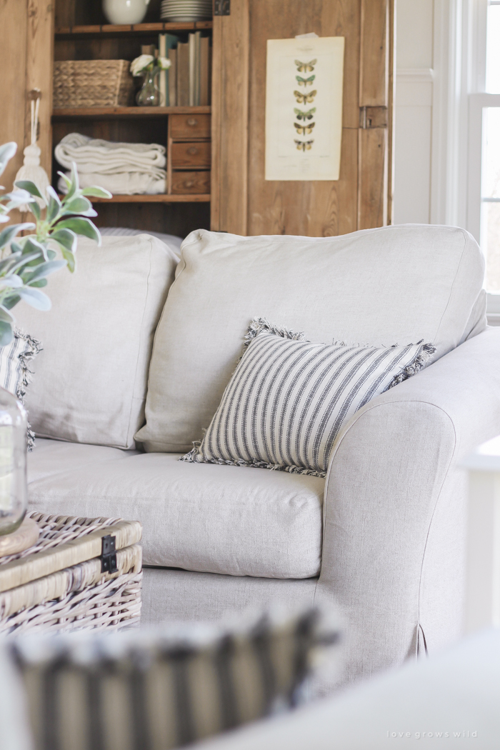 A cozy farmhouse living room with beautiful linen slipcovered sofas. See how to get this custom slipcovered look at LoveGrowsWild.com!