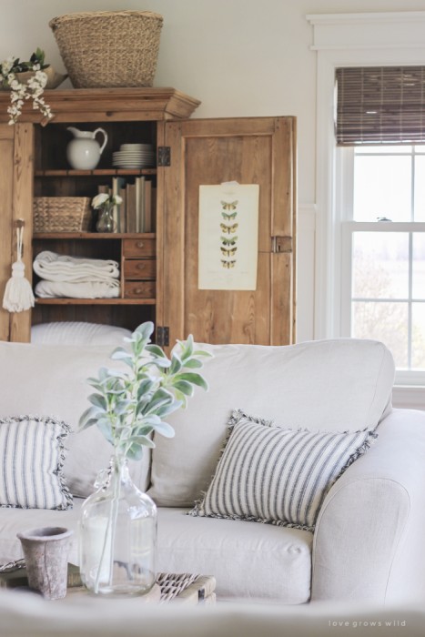 A cozy farmhouse living room with beautiful linen slipcovered sofas. See how to get this custom slipcovered look at LoveGrowsWild.com!