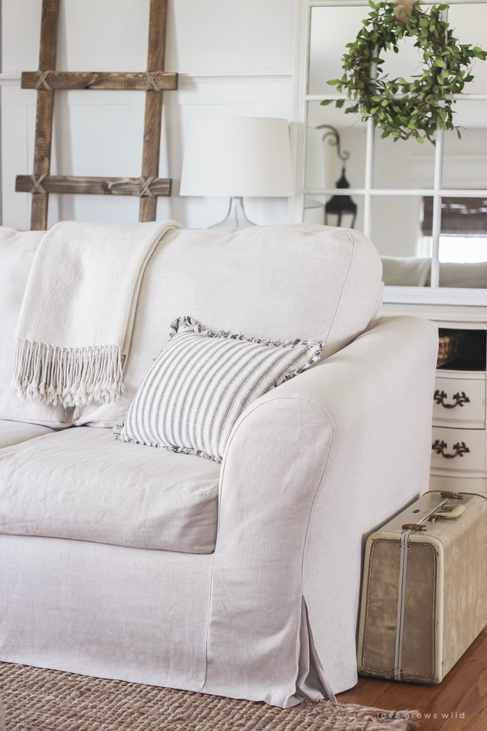 A cozy farmhouse living room with beautiful linen slipcovered sofas. See how to get this custom slipcovered look at LoveGrowsWild.com!