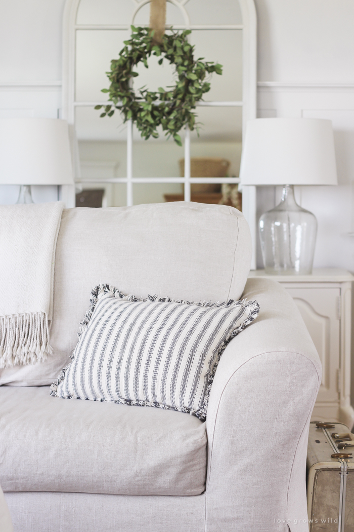 A cozy farmhouse living room with beautiful linen slipcovered sofas. See how to get this custom slipcovered look at LoveGrowsWild.com!