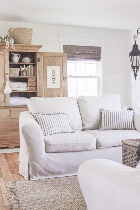A cozy farmhouse living room with beautiful linen slipcovered sofas. See how to get this custom slipcovered look at LoveGrowsWild.com!