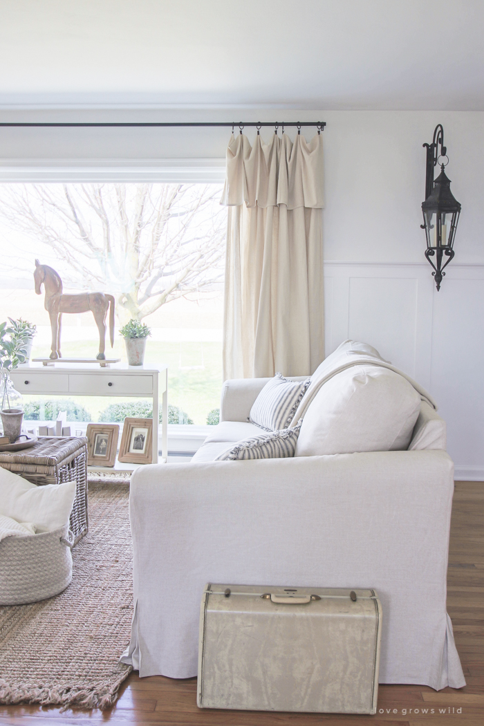 A cozy farmhouse living room with beautiful linen slipcovered sofas. See how to get this custom slipcovered look at LoveGrowsWild.com!