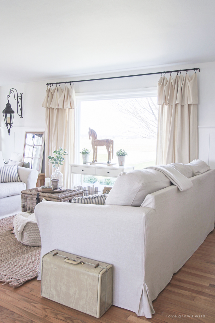 A cozy farmhouse living room with beautiful linen slipcovered sofas. See how to get this custom slipcovered look at LoveGrowsWild.com!