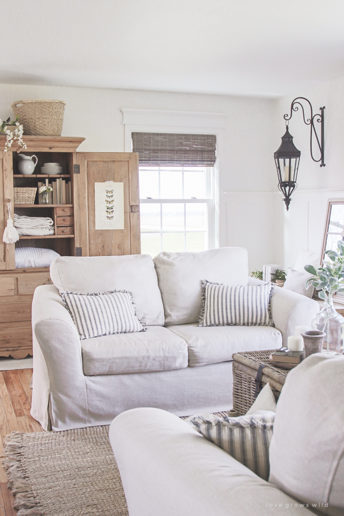 A cozy farmhouse living room with beautiful linen slipcovered sofas. See how to get this custom slipcovered look at LoveGrowsWild.com!