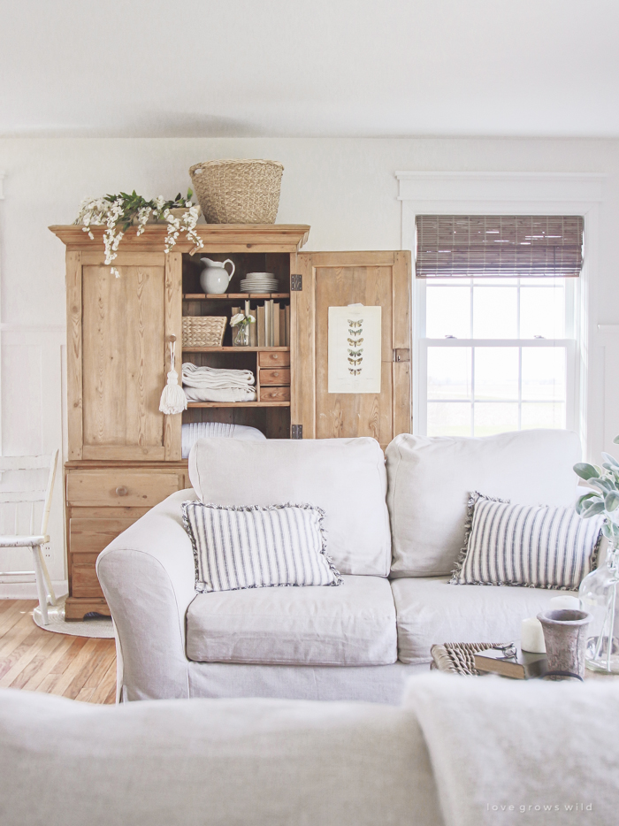 A cozy farmhouse living room with beautiful linen slipcovered sofas. See how to get this custom slipcovered look at LoveGrowsWild.com!