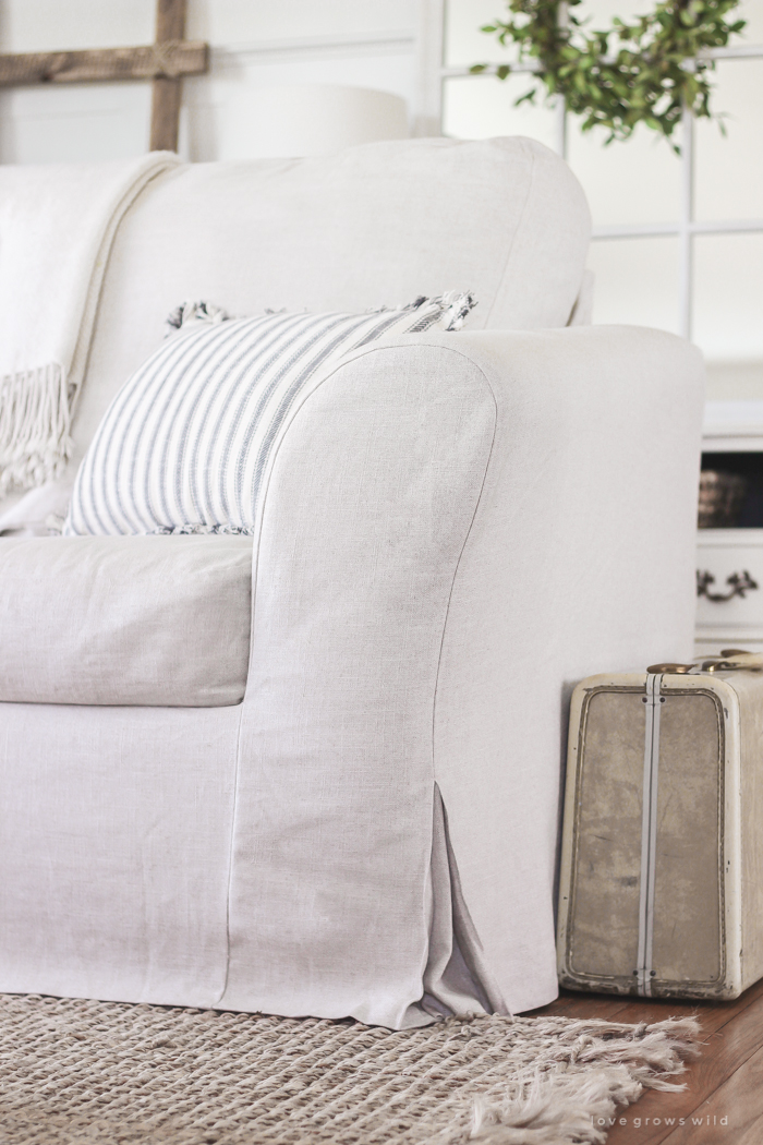 A cozy farmhouse living room with beautiful linen slipcovered sofas. See how to get this custom slipcovered look at LoveGrowsWild.com!