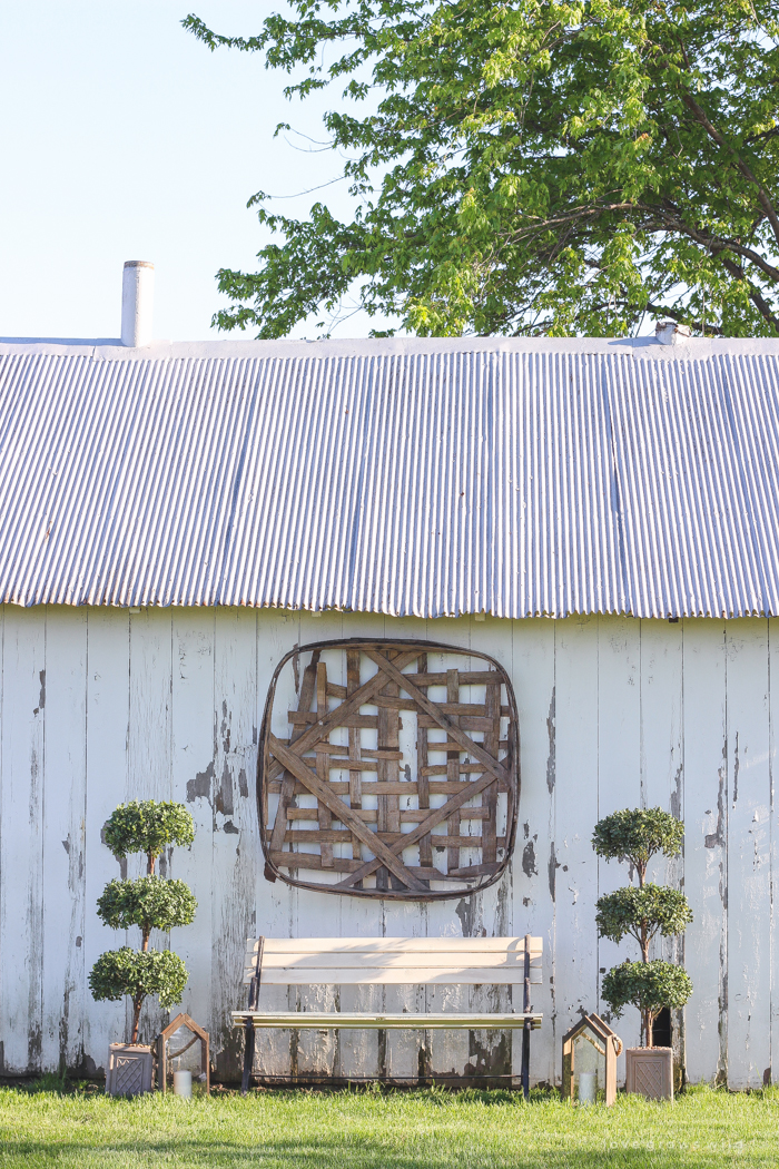 Outdoor decorating ideas including urn planters, an antique tobacco basket, boxwood topiaries and more! See more of this charming white barn at LoveGrowsWild.com