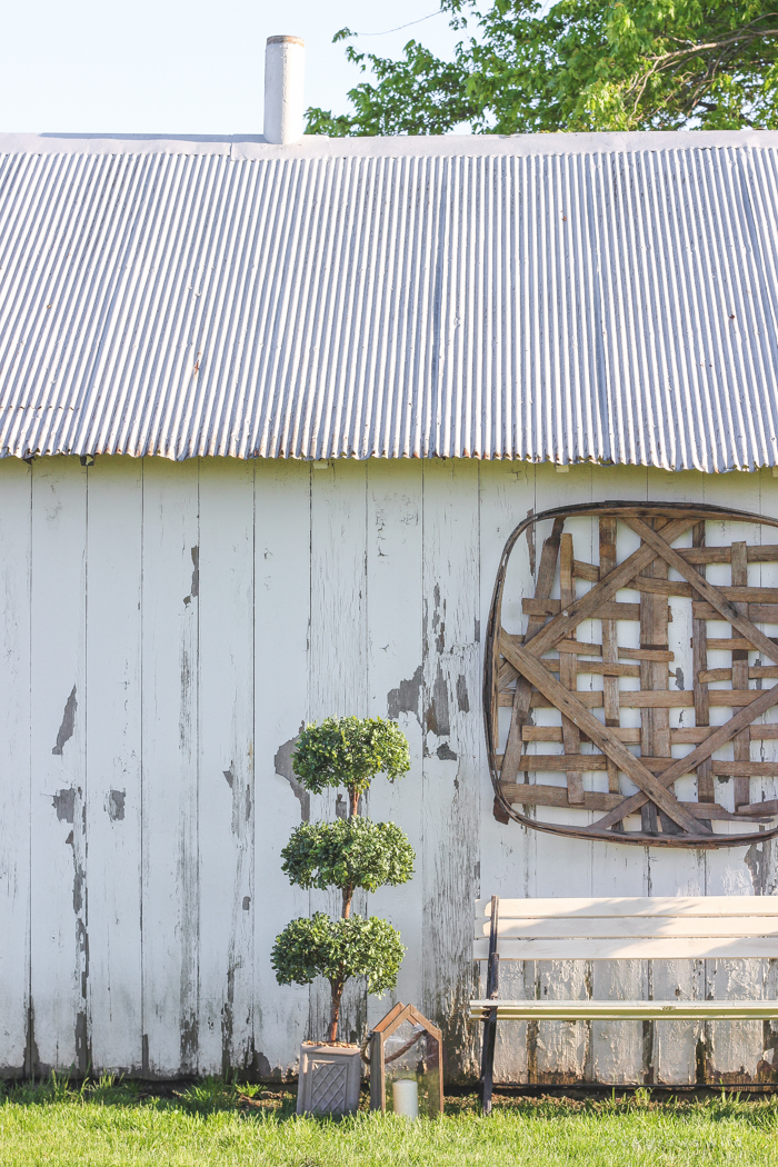 Outdoor decorating ideas including urn planters, an antique tobacco basket, boxwood topiaries and more! See more of this charming white barn at LoveGrowsWild.com