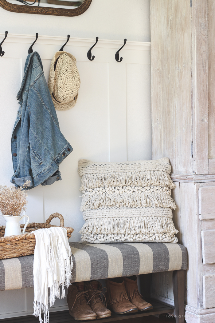 This beautiful farmhouse entryway is the perfect mix of style and organization with a cozy bench, hooks for coat storage, and a basket for accessories.