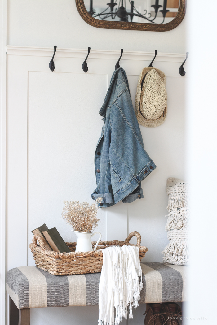 This beautiful farmhouse entryway is the perfect mix of style and organization with a cozy bench, hooks for coat storage, and a basket for accessories. 