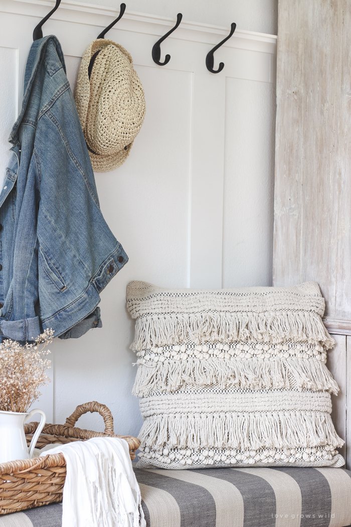 This beautiful farmhouse entryway is the perfect mix of style and organization with a cozy bench, hooks for coat storage, and a basket for accessories. 