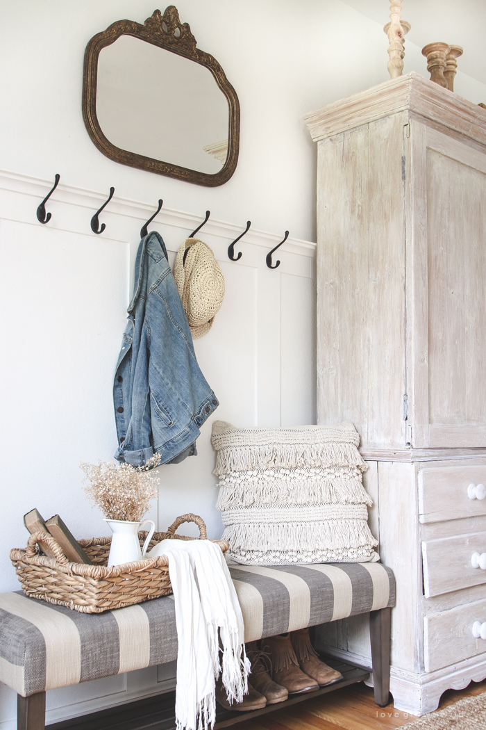 This beautiful farmhouse entryway is the perfect mix of style and organization with a cozy bench, hooks for coat storage, and a basket for accessories. 