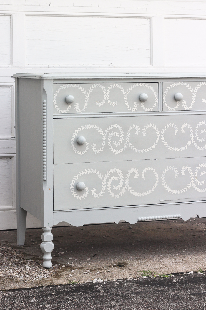 An old dresser gets a makeover with soft blue paint and a delicate hand painted design