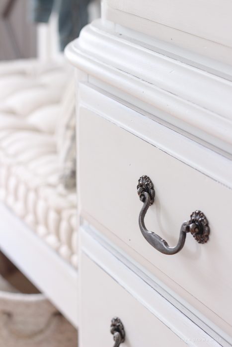 A dark and dated armoire gets a makeover with creamy white paint and beautifully distressed details. Find out how to easily antique furniture with this tutorial!