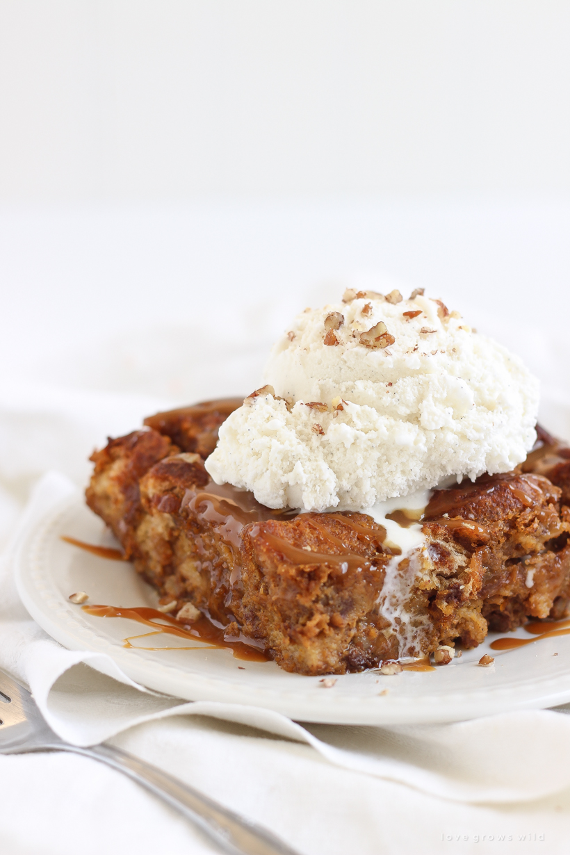 Warm pumpkin bread pudding fresh out of the oven served a la mode with a drizzle of salted caramel and chopped pecans sprinkled on top. Get the recipe at LoveGrowsWild.com