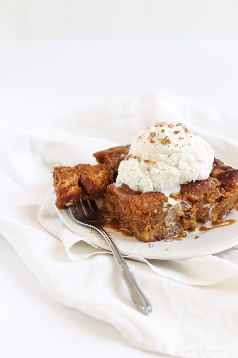 Warm pumpkin bread pudding fresh out of the oven served a la mode with a drizzle of salted caramel and chopped pecans sprinkled on top. Get the recipe at LoveGrowsWild.com