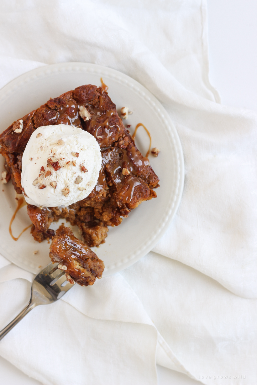 Warm pumpkin bread pudding fresh out of the oven served a la mode with a drizzle of salted caramel and chopped pecans sprinkled on top. Get the recipe at LoveGrowsWild.com