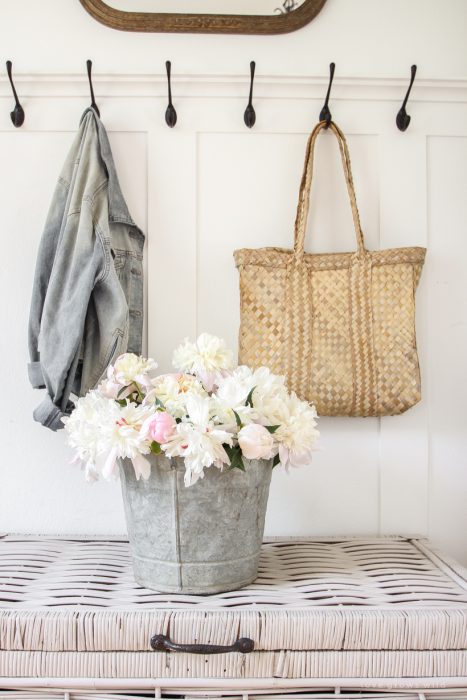 Bucket of peonies styled in an entryway