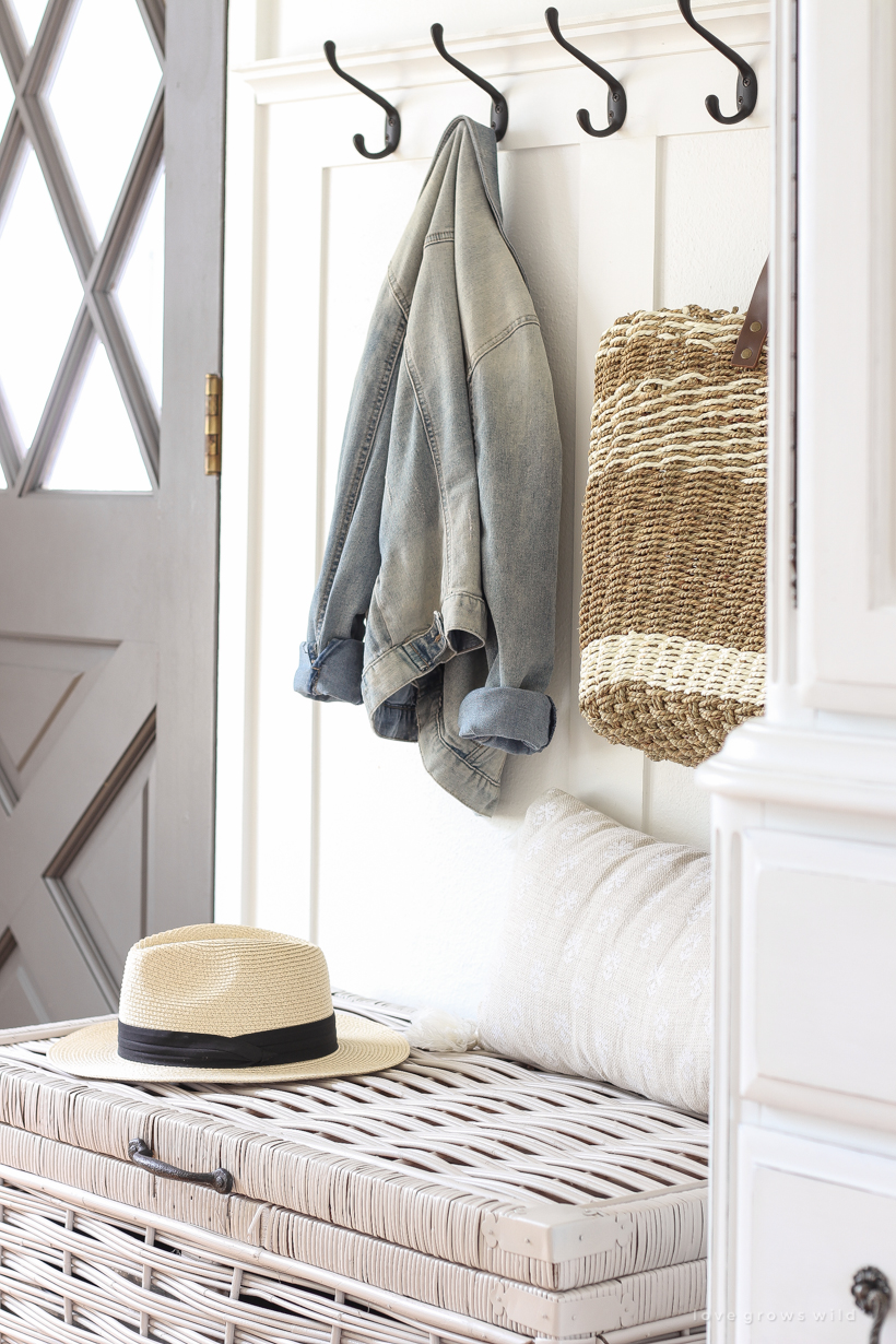 Beautiful styled entryway with coat hooks and wicker trunk