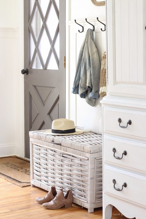 Beautiful styled entryway with coat hooks and wicker trunk