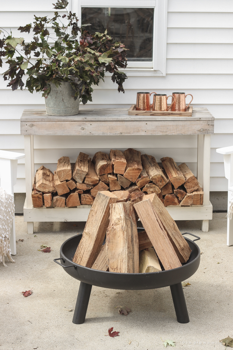 A cozy outdoor space to relax in with a simple fire pit, white adirondack chairs, and beautiful fall decor. See more details at lovegrowswild.com