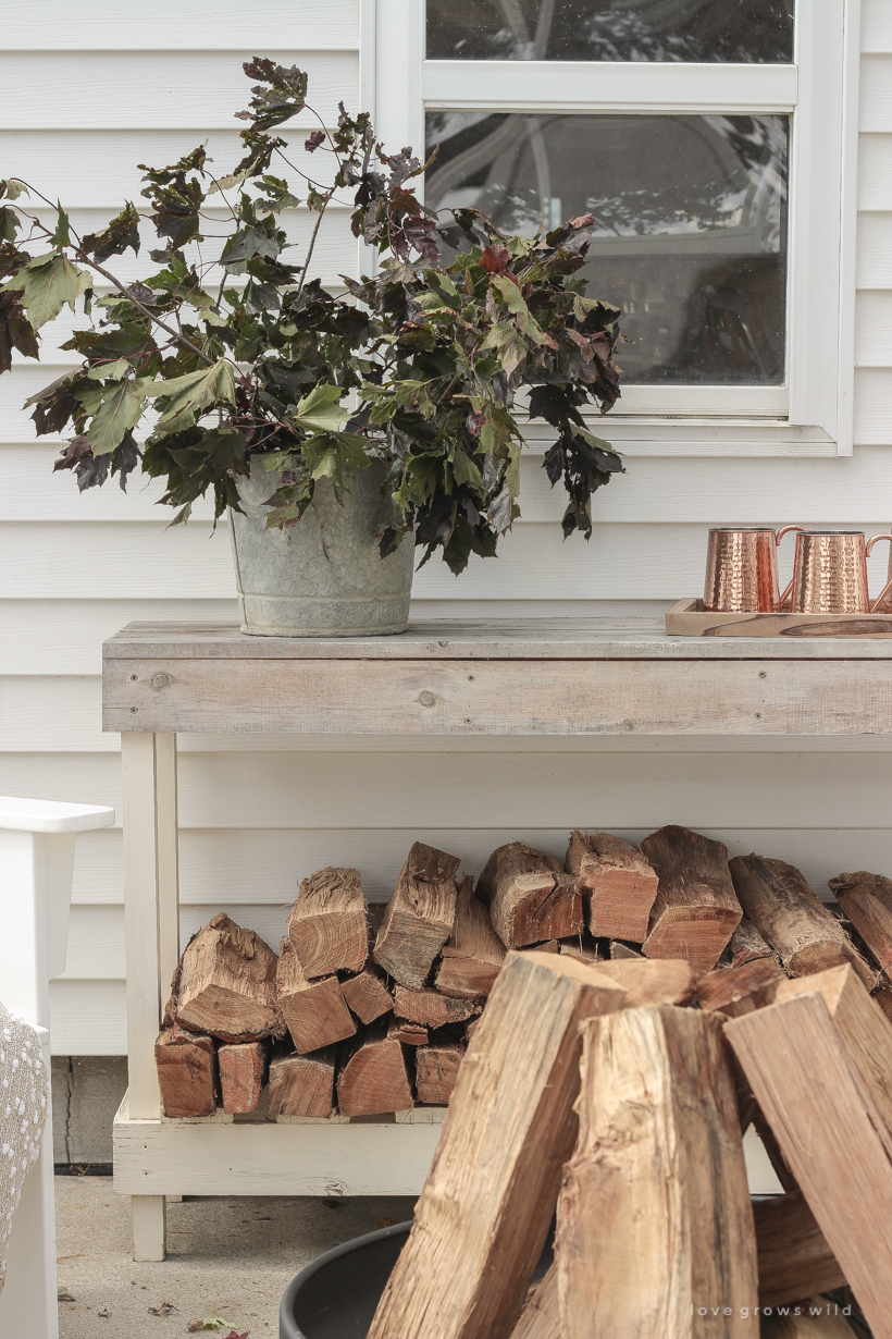 A cozy outdoor space to relax in with a simple fire pit, white adirondack chairs, and beautiful fall decor. See more details at lovegrowswild.com