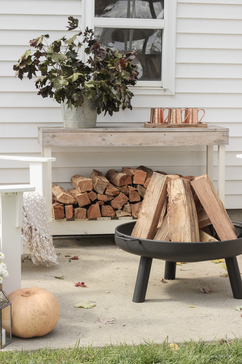 A cozy outdoor space to relax in with a simple fire pit, white adirondack chairs, and beautiful fall decor. See more details at lovegrowswild.com