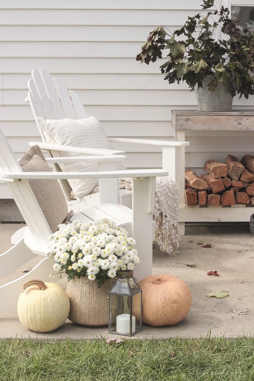 A cozy outdoor space to relax in with a simple fire pit, white adirondack chairs, and beautiful fall decor. See more details at lovegrowswild.com