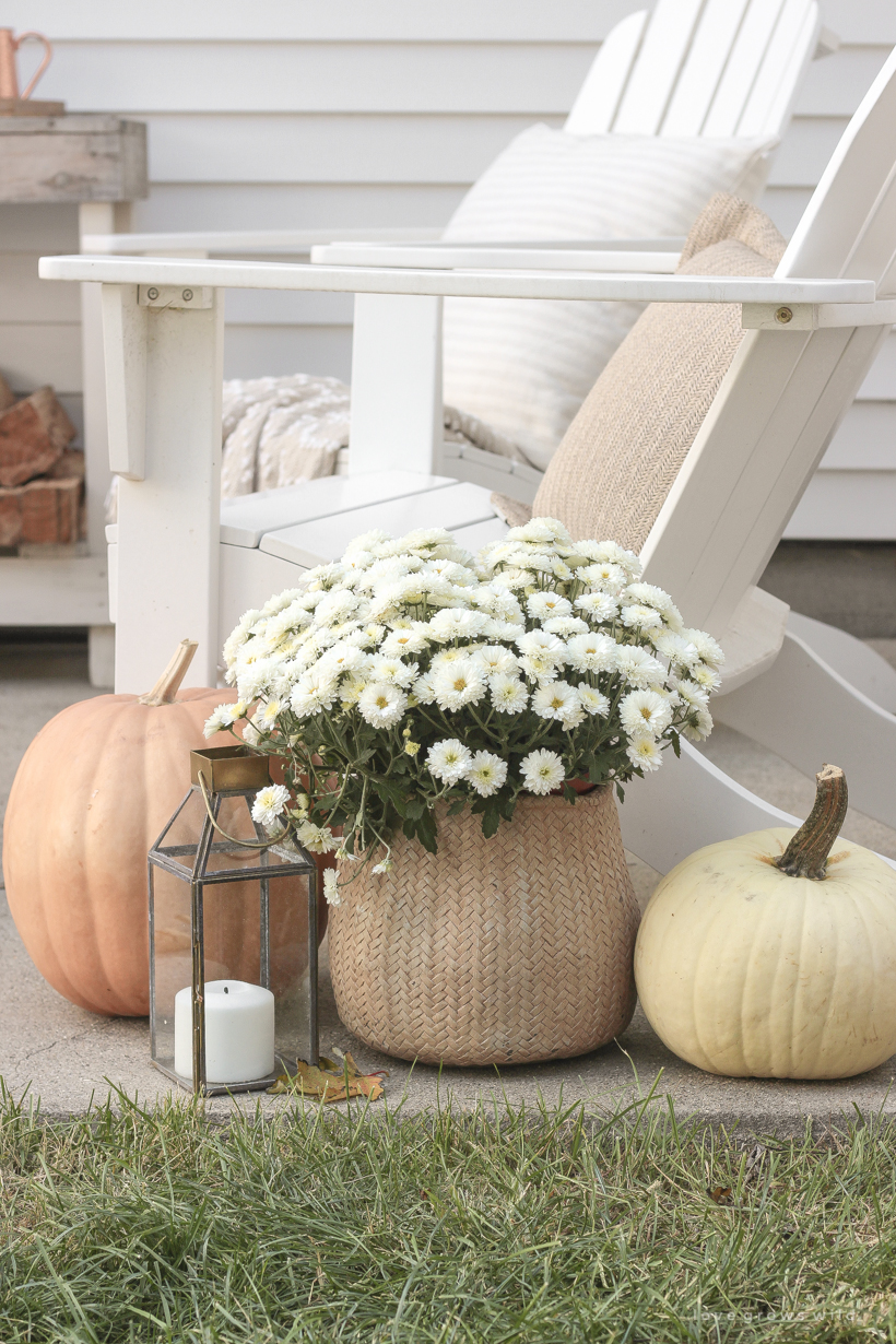 A cozy outdoor space to relax in with a simple fire pit, white adirondack chairs, and beautiful fall decor. See more details at lovegrowswild.com