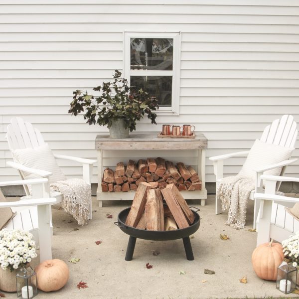 A cozy outdoor space to relax in with a simple fire pit, white adirondack chairs, and beautiful fall decor. See more details at lovegrowswild.com