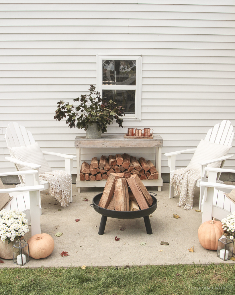 A cozy outdoor space to relax in with a simple fire pit, white adirondack chairs, and beautiful fall decor. See more details at lovegrowswild.com